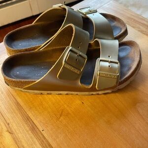 Birkenstock women’s gold Arizona leather sandals.